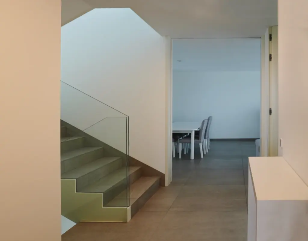 Escadas com guardas de vidro e hall dos quartos e sala